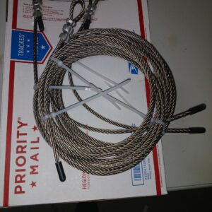 Coiled steel cable with two metal rods on a USPS Priority Mail box.